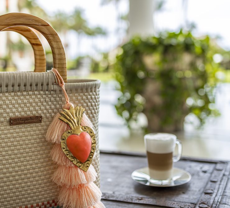 Handcrafted woven bag with tassel decoration beside a coffee cup at a luxury resort.