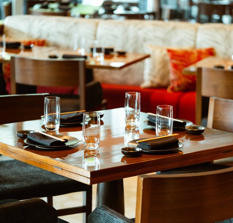 Elegant dining table setup inside Novikov Miami featuring modern wood furniture, glassware, and contemporary décor.