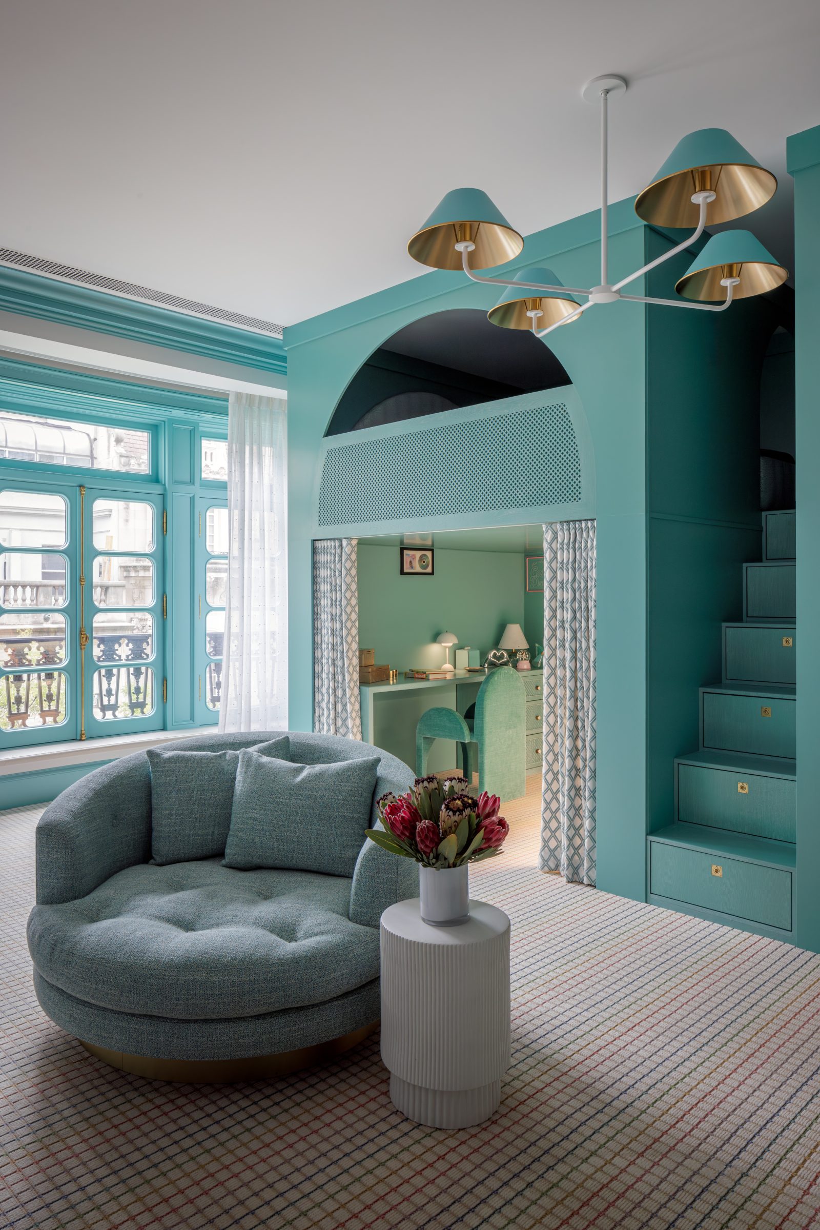 Playful kids room designed by Genevieve Lake featuring teal walls, built-in staircase with storage, and cozy reading nook.