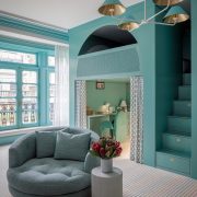 Playful kids room designed by Genevieve Lake featuring teal walls, built-in staircase with storage, and cozy reading nook.