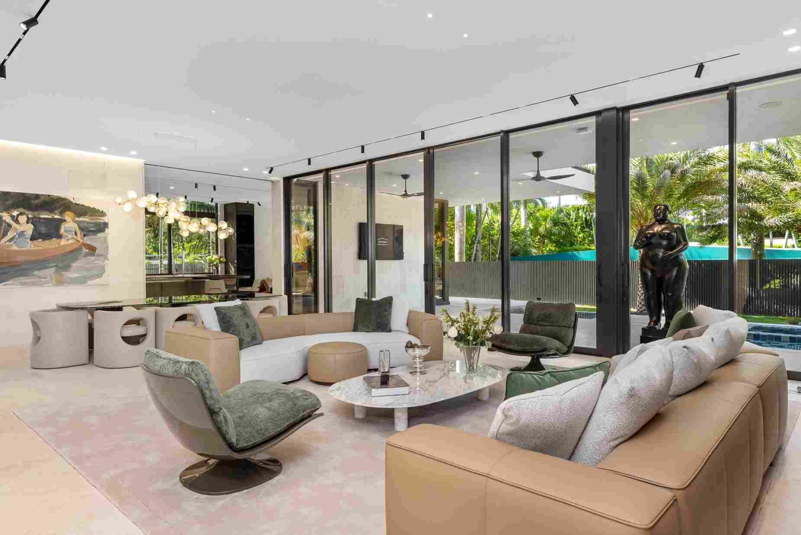 Living room of luxury estate on Sunset Islands featuring floor-to-ceiling windows, neutral décor, and tropical garden views.