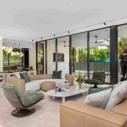 Living room of luxury estate on Sunset Islands featuring floor-to-ceiling windows, neutral décor, and tropical garden views.