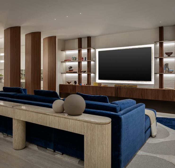 Contemporary media room designed by Genevieve Lake featuring navy velvet seating, wood panel accents, and built-in shelving.