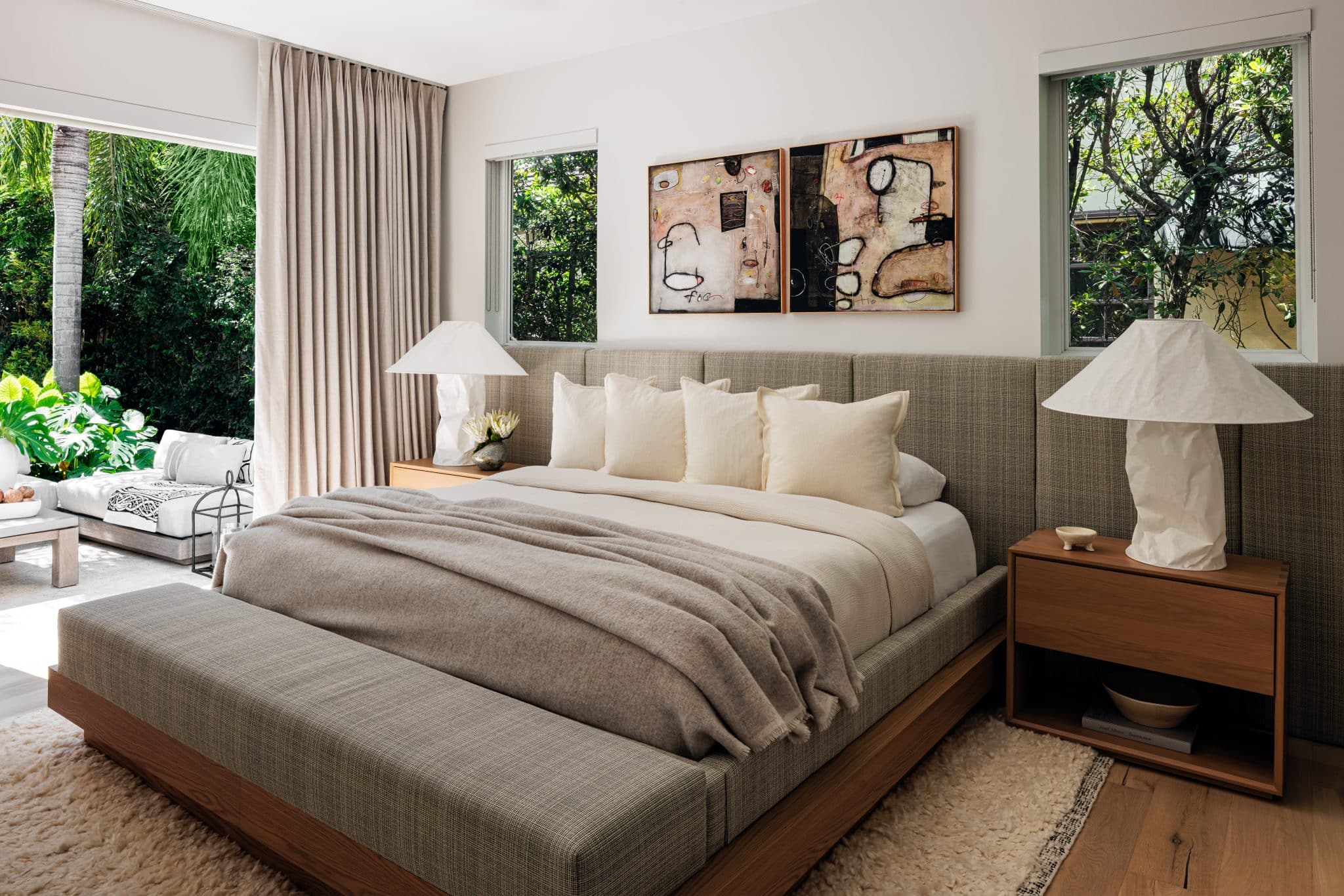 Serene bedroom with neutral tones, layered textures, and palm tree views.
