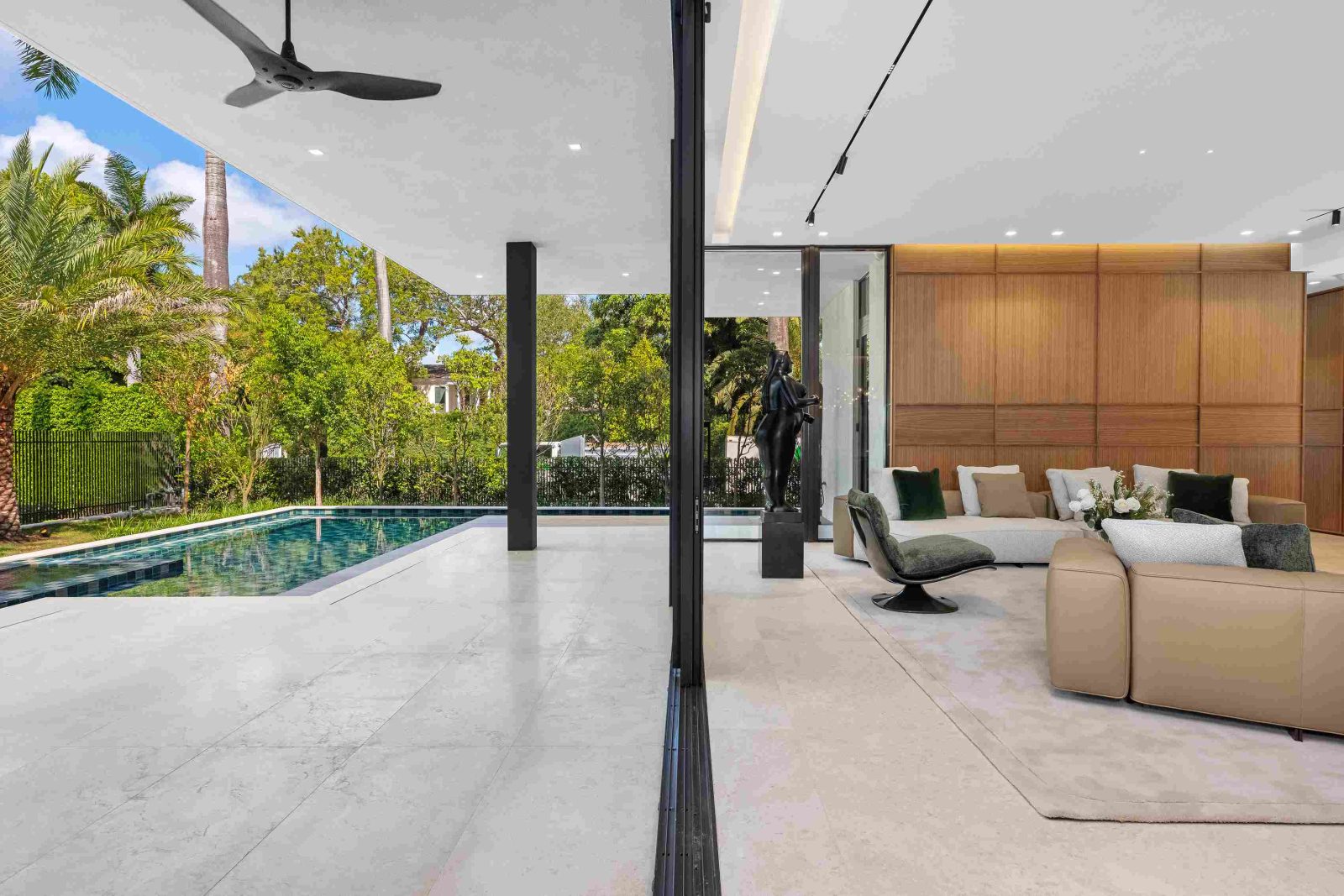 Outdoor living area with infinity pool and tropical landscaping at modern Miami Beach estate.