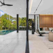 Outdoor living area with infinity pool and tropical landscaping at modern Miami Beach estate.