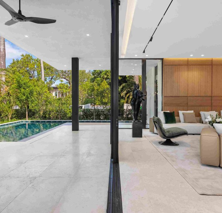 Outdoor living area with infinity pool and tropical landscaping at modern Miami Beach estate.