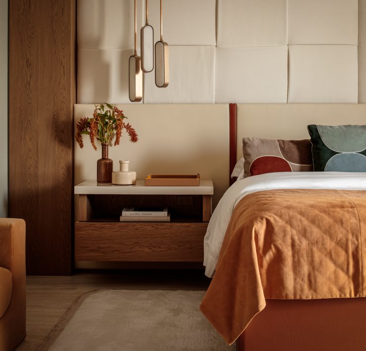 Primary bedroom designed by Genevieve Lake featuring warm earth tones, upholstered headboard, and modern pendant lighting.