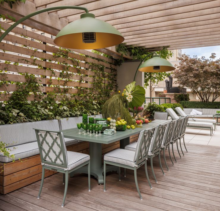 Rooftop terrace designed by Genevieve Lake featuring outdoor dining area, greenery, and modern pergola with pendant lighting.