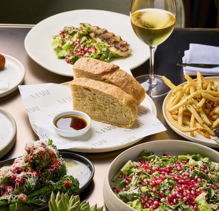 Mediterranean lunch set with salad, bread, and wine at ADRIFT Mare Miami.