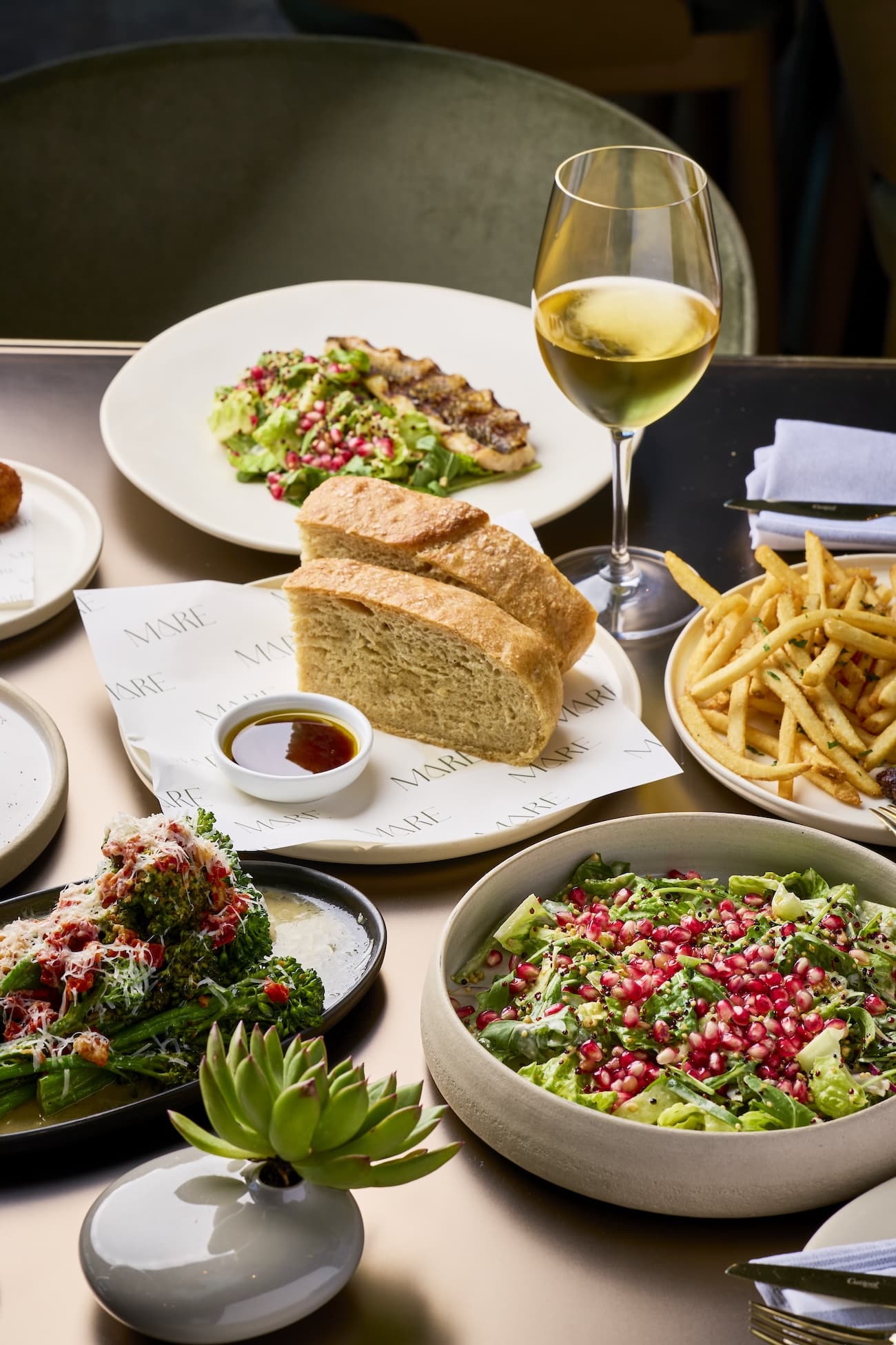 Mediterranean lunch set with salad, bread, and wine at ADRIFT Mare Miami.