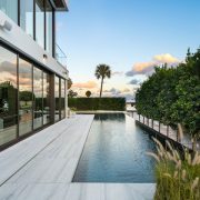 Heated infinity pool and terrace with sleek marble finishes and tropical landscaping at Casa Moderne, Bay Point, Miami.