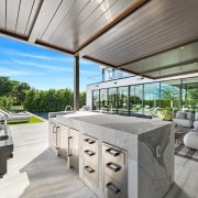 Casa Moderne’s outdoor kitchen and lounge area featuring marble countertops, modern pergola, and lush garden views in Bay Point, Miami.