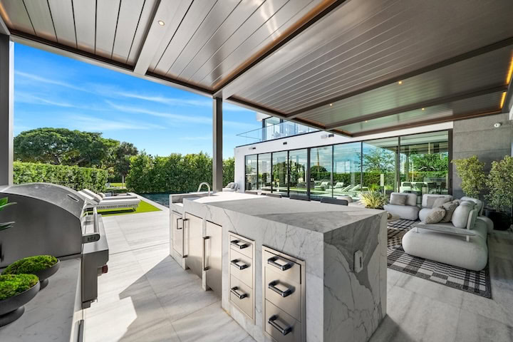 Casa Moderne’s outdoor kitchen and lounge area featuring marble countertops, modern pergola, and lush garden views in Bay Point, Miami.