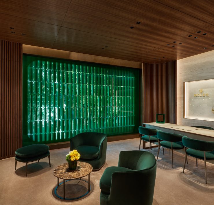 Private consultation lounge with emerald chairs, wood ceiling, and refined interior finishes in luxury showroom