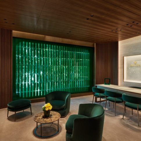 Private consultation lounge with emerald chairs, wood ceiling, and refined interior finishes in luxury showroom