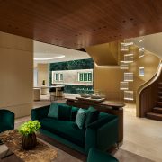 Luxury boutique lounge with emerald seating and sculptural staircase leading to second level