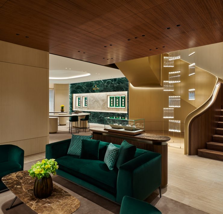 Luxury boutique lounge with emerald seating and sculptural staircase leading to second level