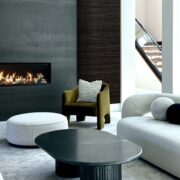 Modern luxury living room by Deborah Gregg Interiors featuring a sleek black fireplace wall, sculptural curved seating, a black statement coffee table, and a textured accent wall with soft neutral tones.