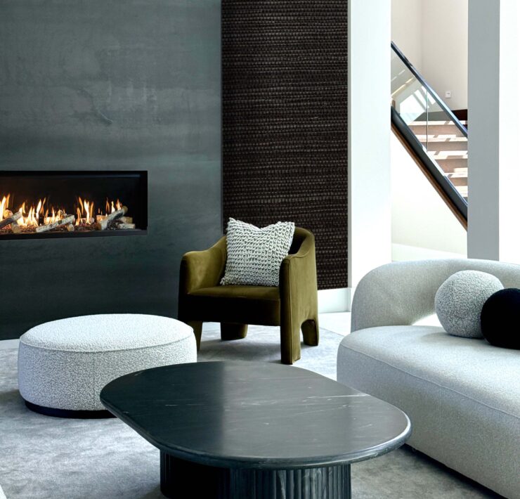 Modern luxury living room by Deborah Gregg Interiors featuring a sleek black fireplace wall, sculptural curved seating, a black statement coffee table, and a textured accent wall with soft neutral tones.