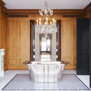 Classic bathroom with freestanding metal tub, marble fireplace, crystal chandelier, and rich wood wall paneling