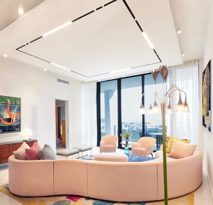Contemporary living room with curved blush sofa, pastel lounge chairs, sculptural floor lamp, and playful abstract rug