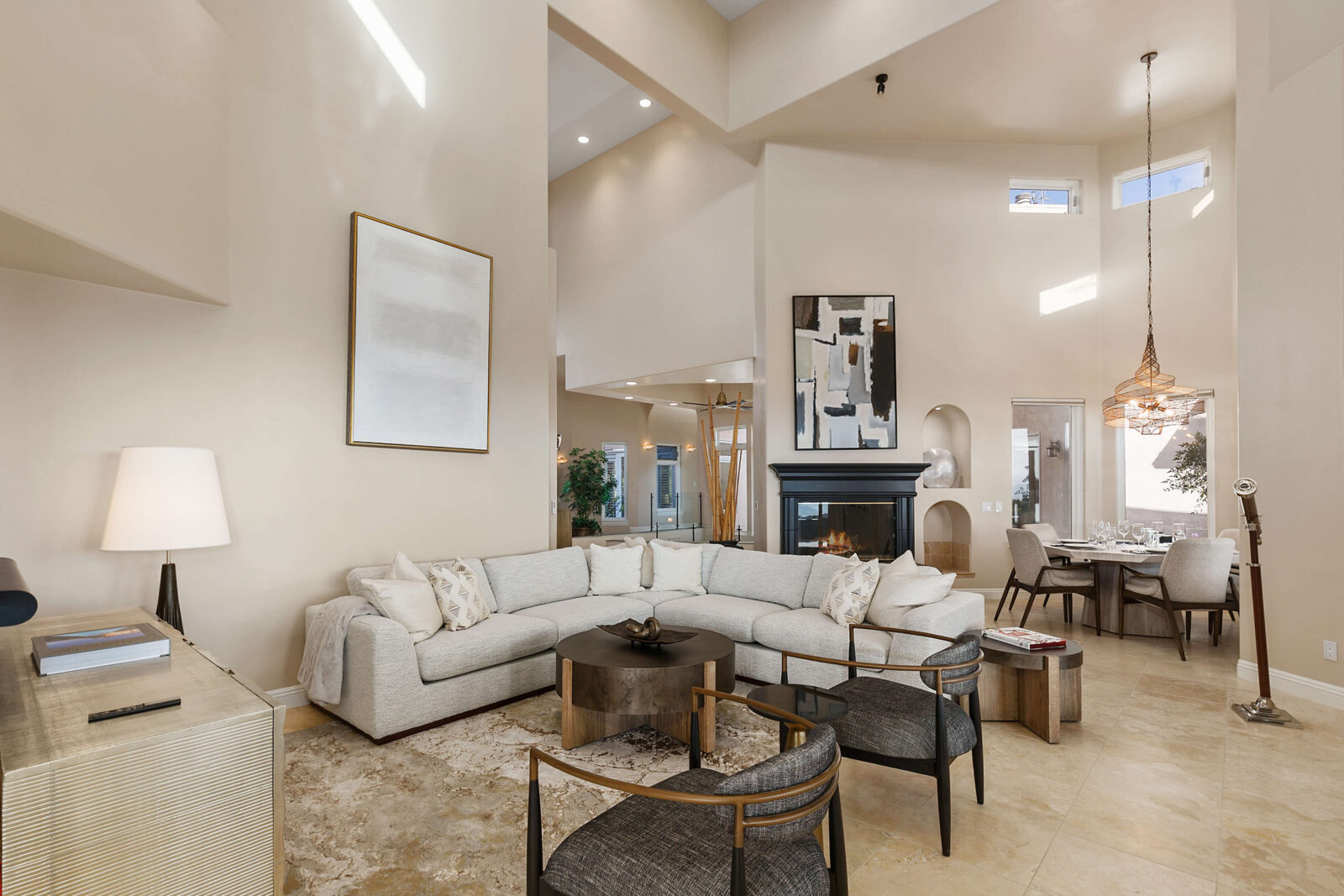 Open-concept living room with soaring ceilings, curved sectional, black fireplace, and adjacent dining area