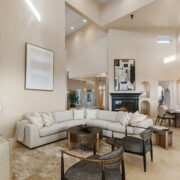 Open-concept living room with soaring ceilings, curved sectional, black fireplace, and adjacent dining area