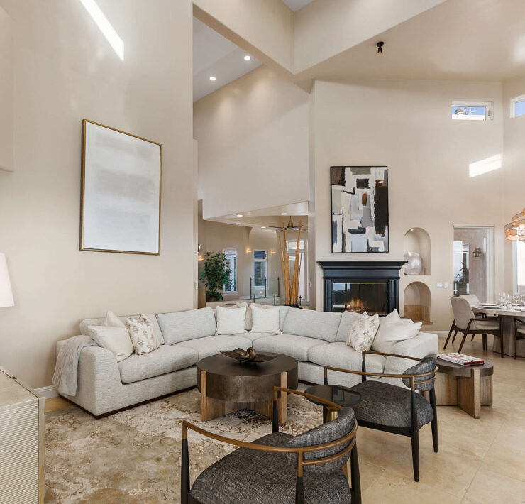 Open-concept living room with soaring ceilings, curved sectional, black fireplace, and adjacent dining area
