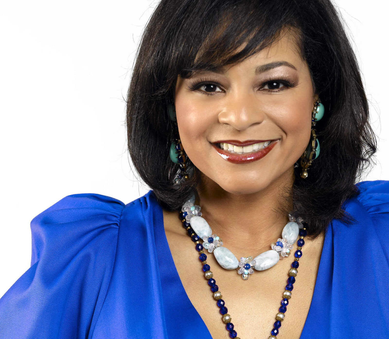 Professional portrait of designer Yvette Craddock wearing a vivid blue dress and statement jewelry