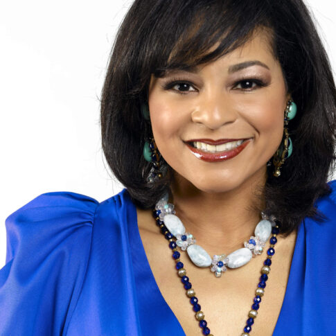 Professional portrait of designer Yvette Craddock wearing a vivid blue dress and statement jewelry