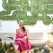 Interior designer seated below geometric moss wall art with cactus arrangements