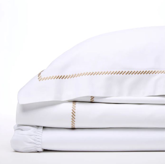 Trousseau Domino Collection white bedding with gold embroidered trim and crisp sheet detailing