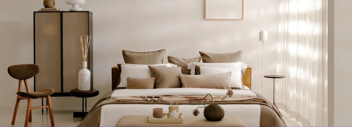 Trousseau Dune Collection bedding styled in a soft neutral bedroom with layered pillows and warm natural textures