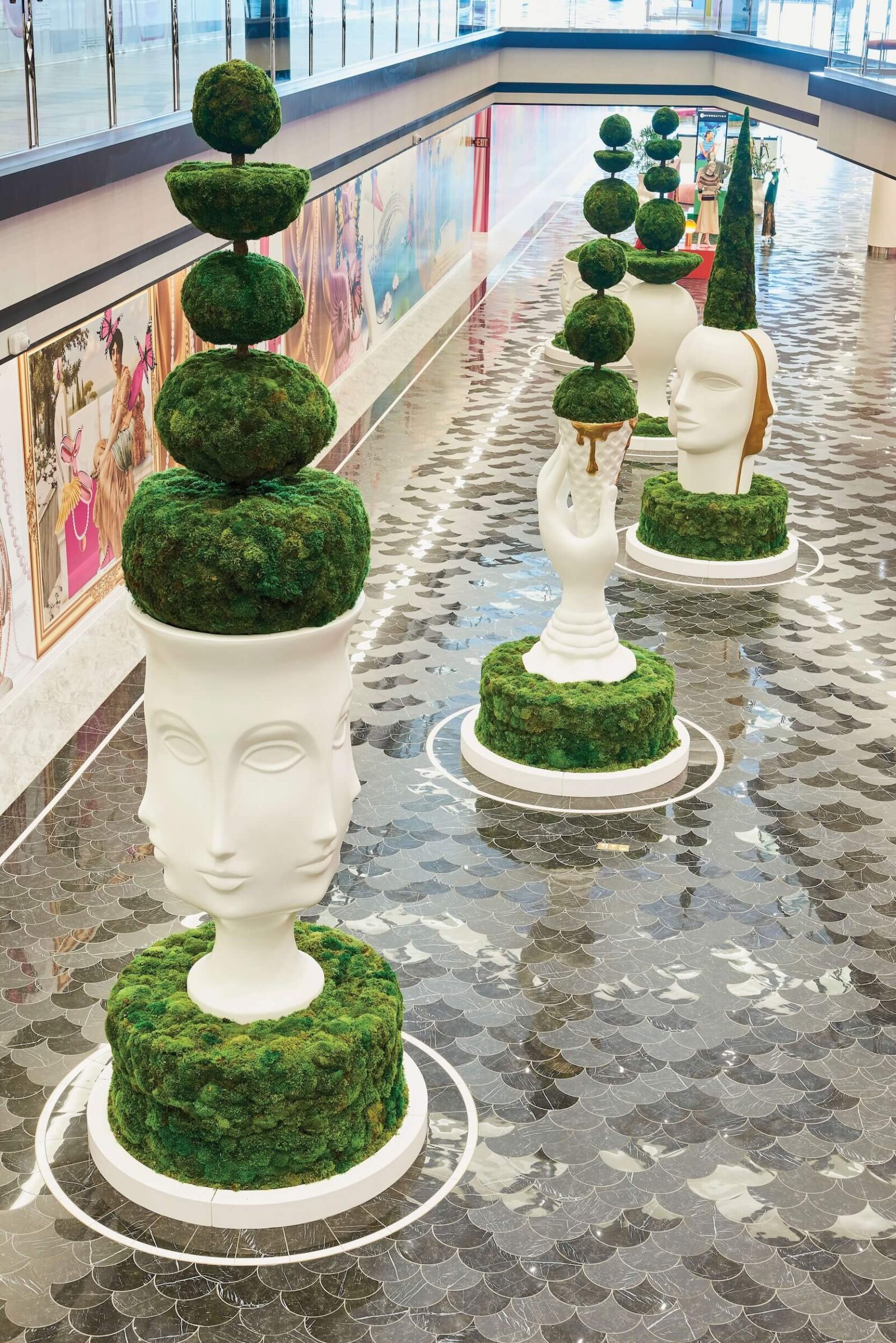 Luxury interior walkway with sculptural moss topiary planters and reflective tile flooring