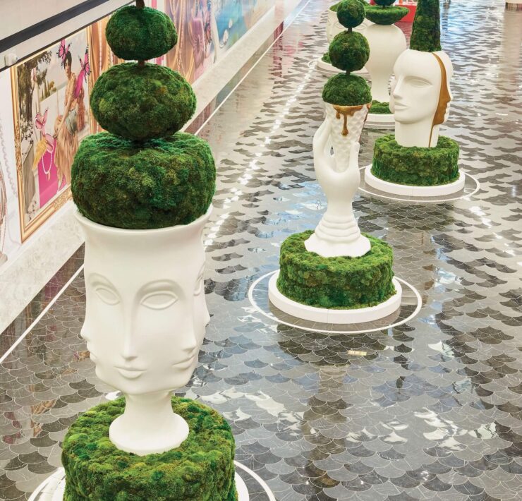 Luxury interior walkway with sculptural moss topiary planters and reflective tile flooring