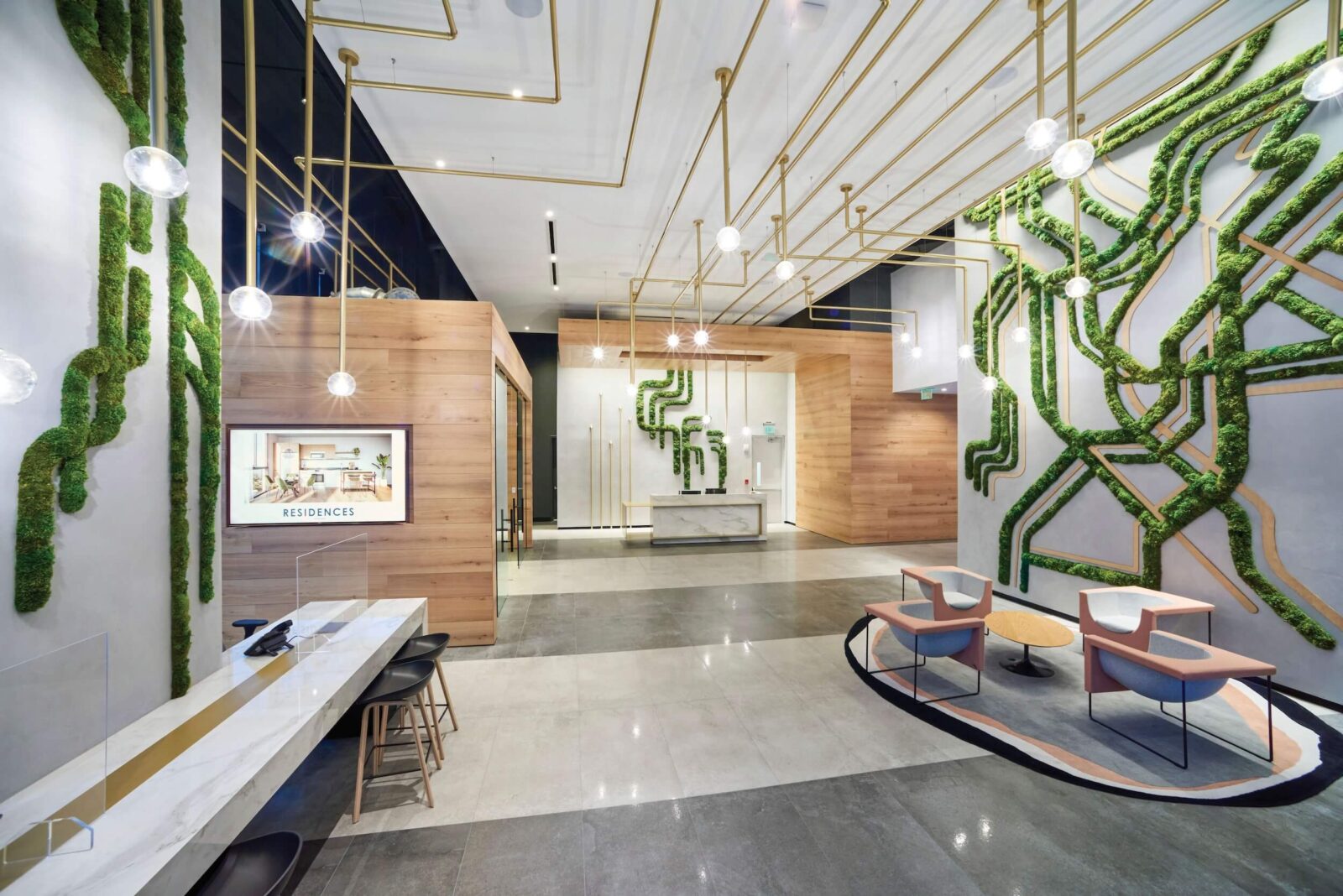 Luxury lobby with moss wall installations, brass lighting, wood accents & modern seating