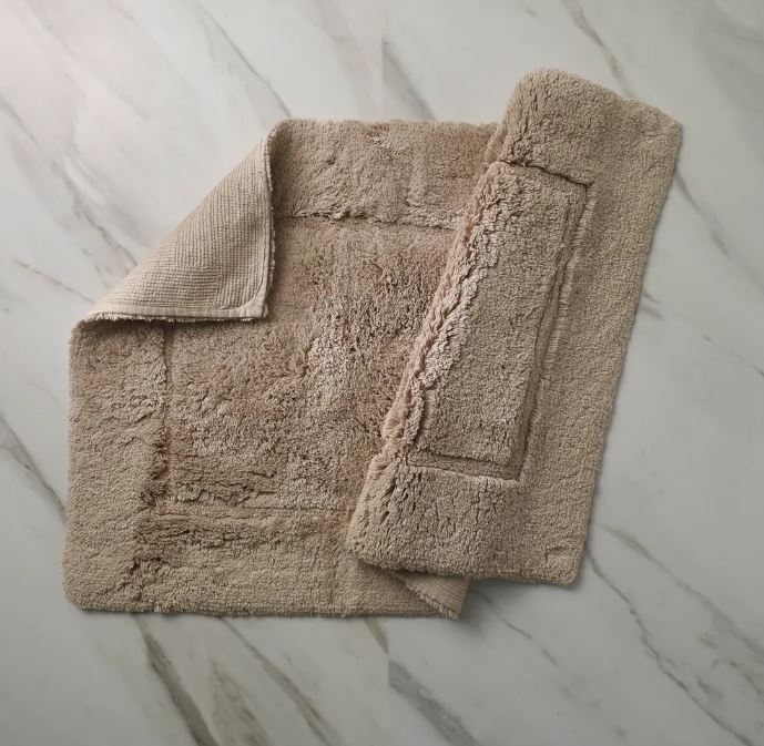 Trousseau Must Bath Rug and bath mat set in soft beige on a marble bathroom floor