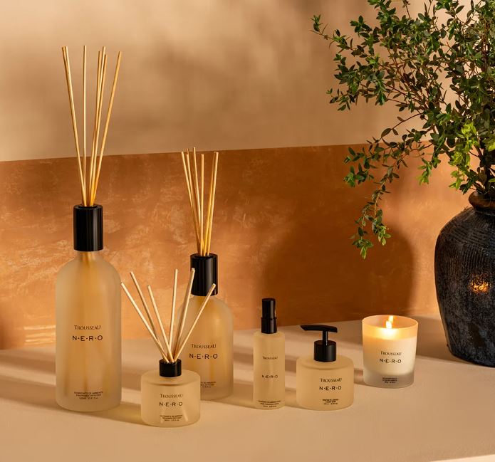 Trousseau Nero Collection home fragrance with diffusers, candle, room spray, and soap in warm amber lighting