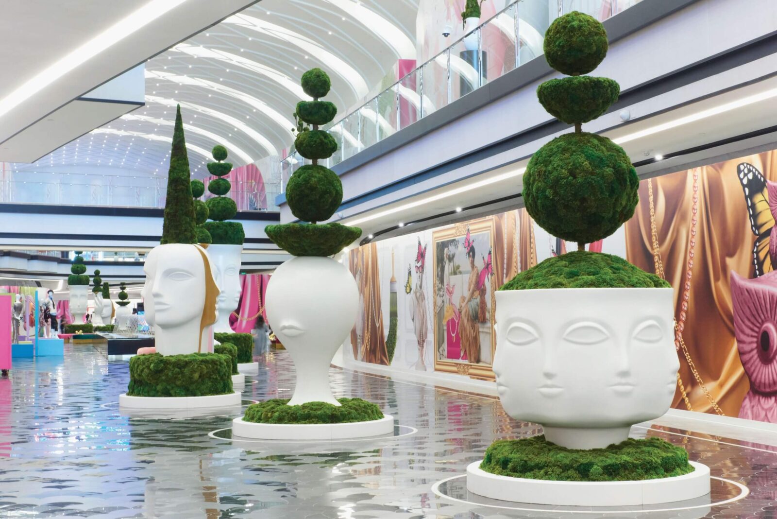 Luxury interior walkway with sculptural moss topiary planters and reflective tile flooring