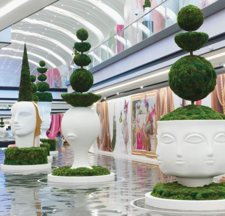 Luxury interior walkway with sculptural moss topiary planters and reflective tile flooring
