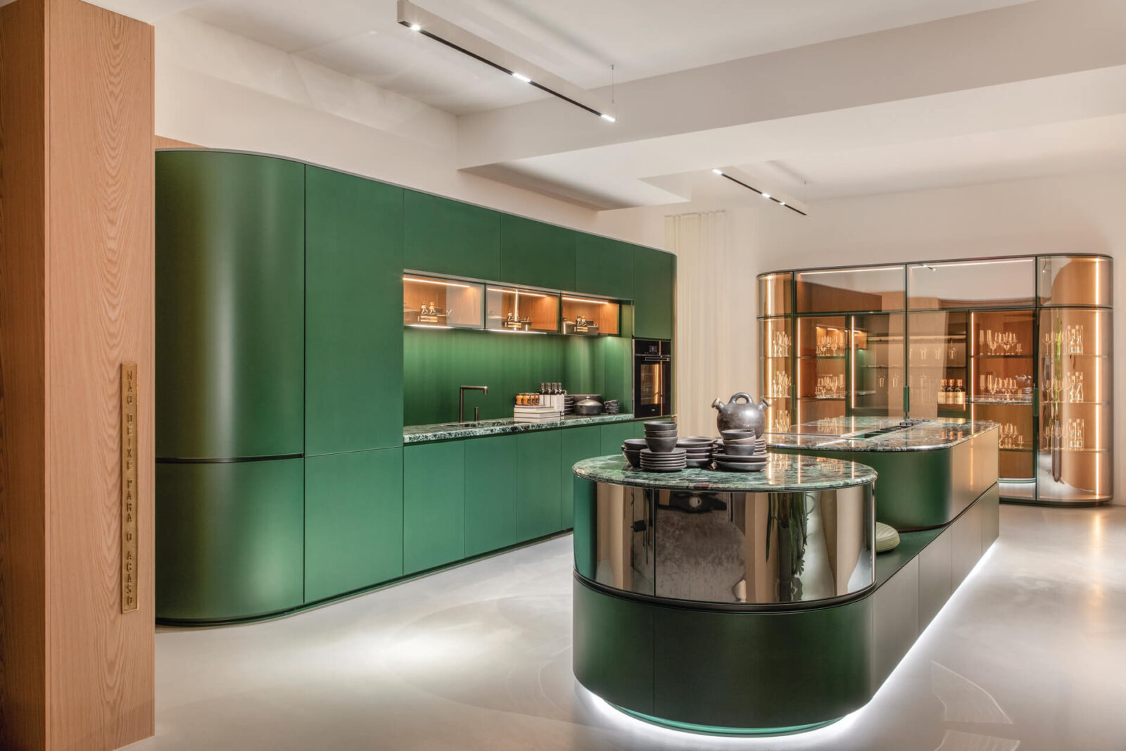 Florense Arco by Pininfarina luxury green kitchen with curved cabinetry, marble surfaces, glass display storage, and integrated lighting.