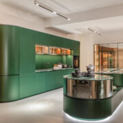 Florense Arco by Pininfarina luxury green kitchen with curved cabinetry, marble surfaces, glass display storage, and integrated lighting.