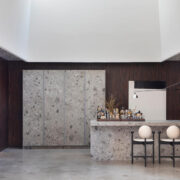 Florense Countertop Sliding System and Vetrata cabinetry with stone bar, dark wood walls, glass shelving, and concealed storage.