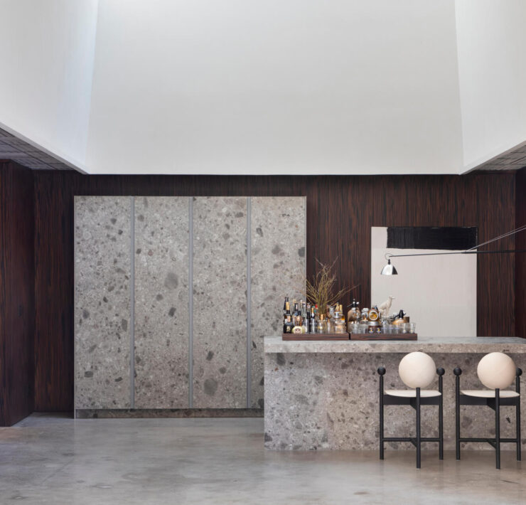 Florense Countertop Sliding System and Vetrata cabinetry with stone bar, dark wood walls, glass shelving, and concealed storage.
