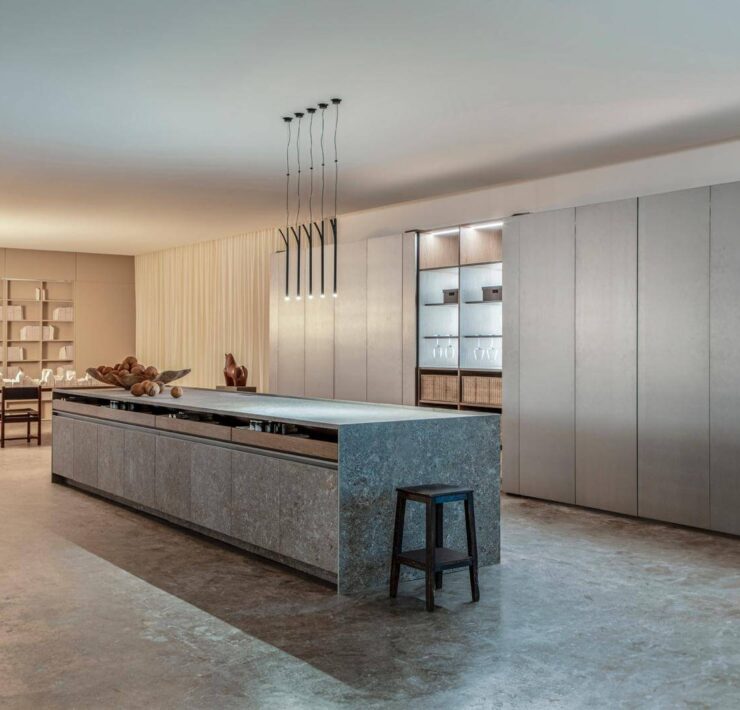 Florense Eclipse III kitchen with concealed panel system, stone island, gray cabinetry, and integrated storage wall.