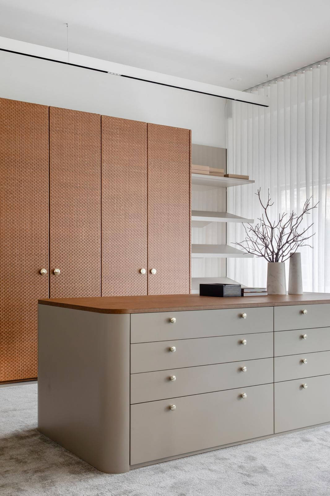 Florense Leather Lined Door closet with woven leather panels, rounded island drawers, brass hardware, and soft neutral finishes.