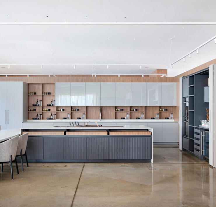 Florense Moderna Kitchen with white and wood cabinetry, large island, integrated appliances, open shelving, and polished concrete floors.