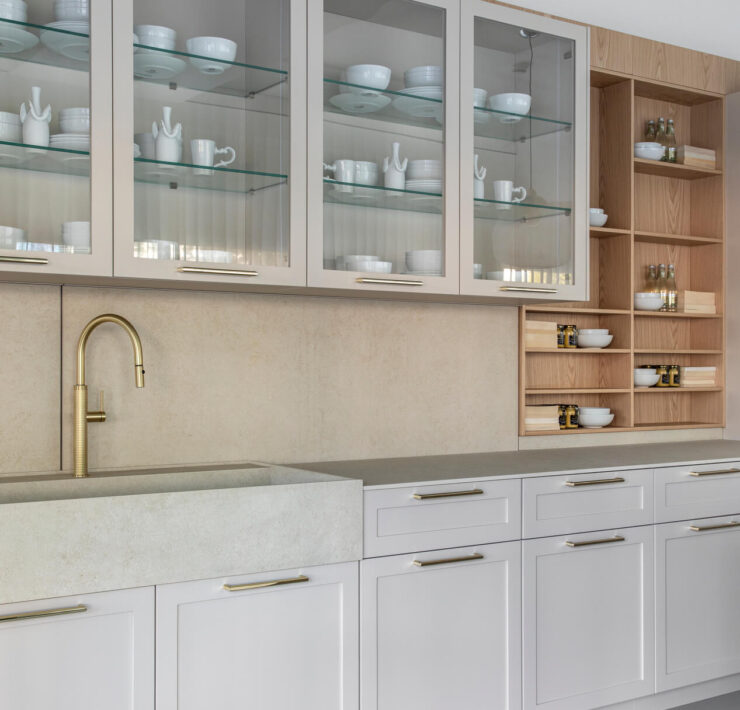 Florense Moldura kitchen cabinetry with glass-front cabinets, brass hardware, white paneling, open wood shelving, and stone sink.
