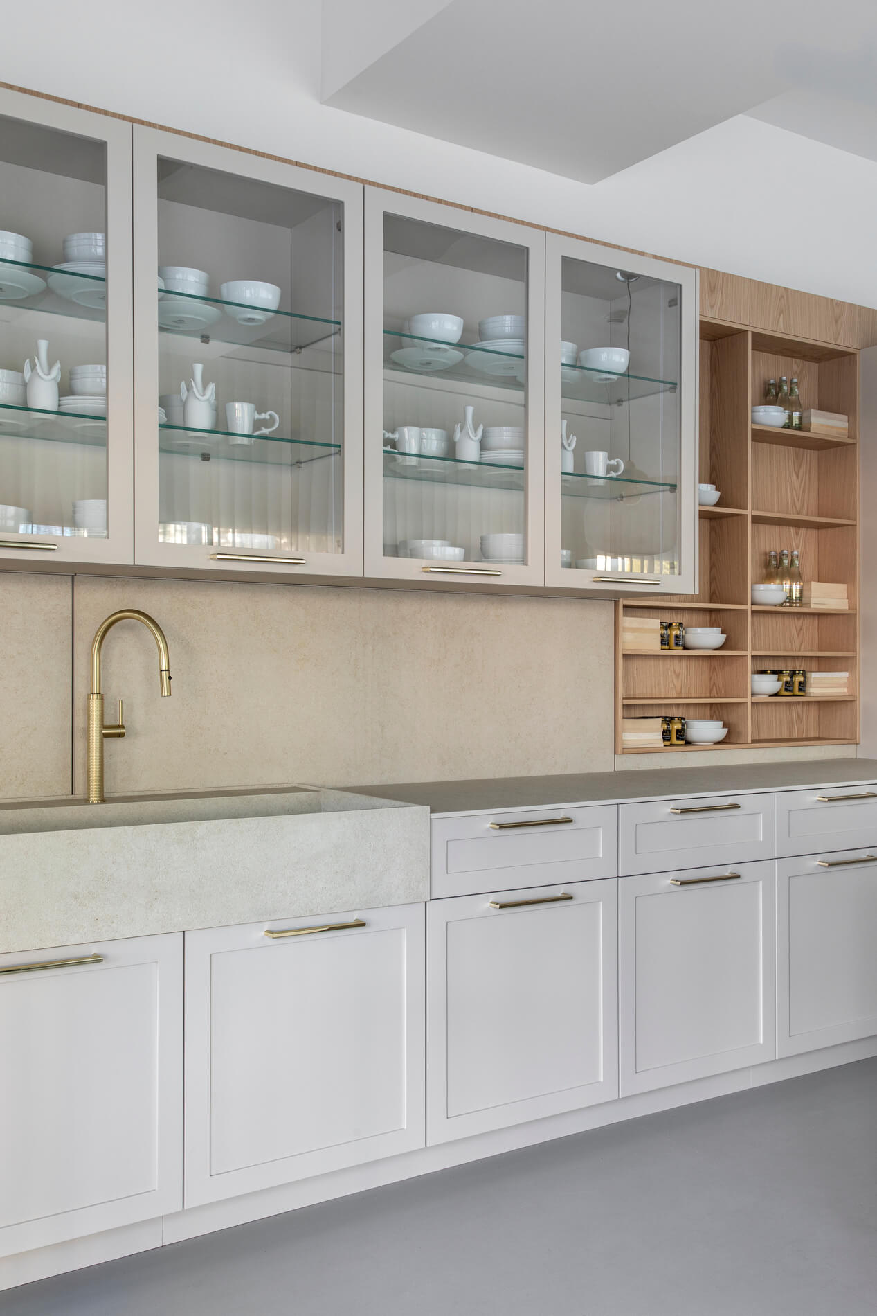 Florense Moldura kitchen cabinetry with glass-front cabinets, brass hardware, white paneling, open wood shelving, and stone sink.